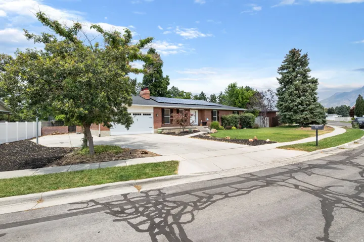 Brick exterior residence with an attached two-car garage, concrete driveway, and established landscaping