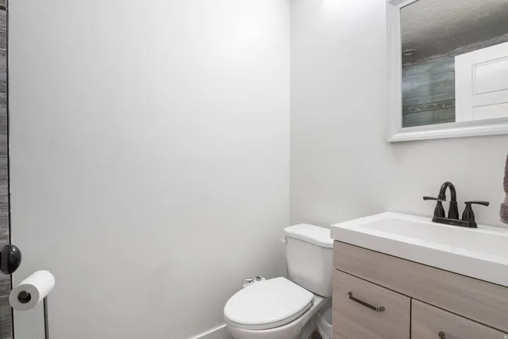 Bathroom featuring a light wood-finish vanity with a white countertop and integrated sink, a framed mirror, and a black faucet