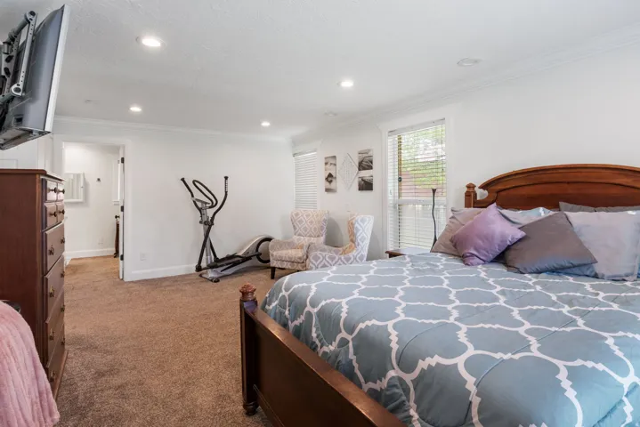 Carpeted interior space featuring a wooden bed frame, recessed lighting, and white trim