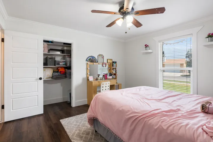 Spacious room featuring wood-finish flooring, white walls, and crown molding