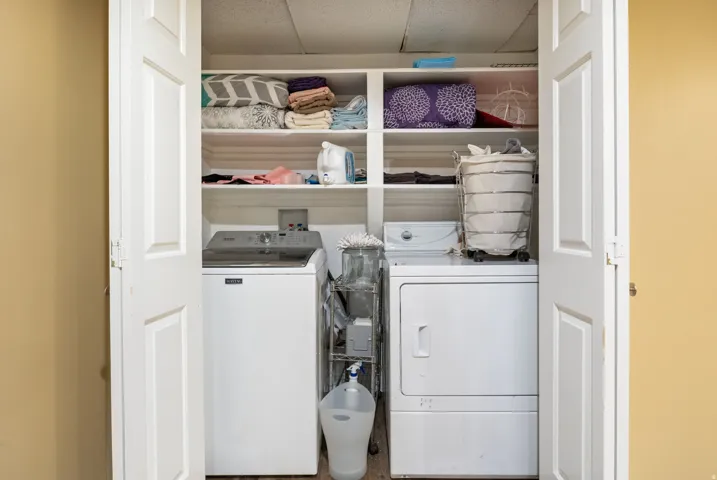 Dedicated laundry closet featuring built-in shelving, a top-load washer, and a front-load dryer