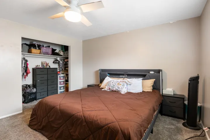 Bedroom featuring a ceiling fan with integrated lighting, neutral wall paint, and gray carpet flooring