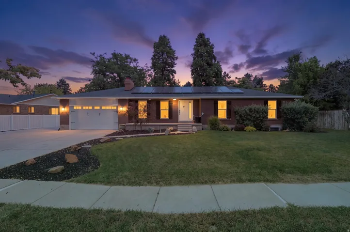 Brick exterior with a prominent two-car garage, solar panels, and a concrete driveway