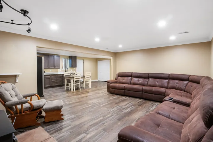 Spacious open-concept room featuring wood-finish flooring, recessed lighting, and crown molding