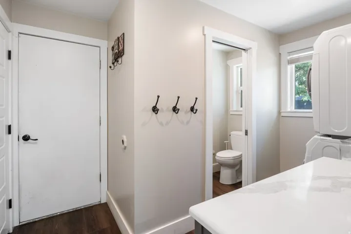 Laundry area with white stackable units, a window with exterior visibility, and a light-toned countertop