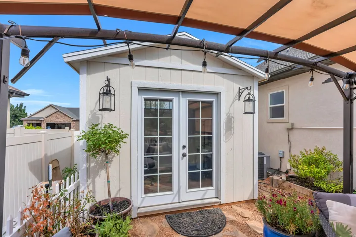 Exterior storage shed featuring double glass-paned doors and two wall-mounted lanterns