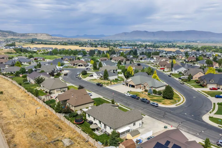 Residential neighborhood featuring a curvilinear street layout, mature landscaping, and mountain backdrop