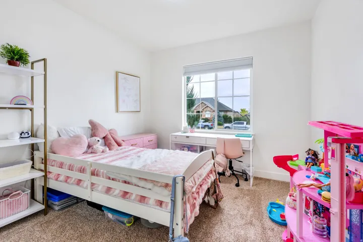 Carpeted room featuring a window with grid patterns, white walls, and a built-in shelving unit with a gold-toned frame
