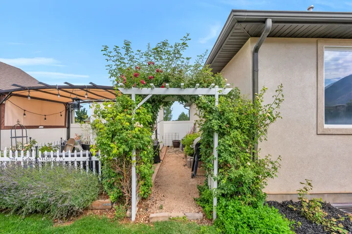 Gravel path with a white pergola archway and lush greenery