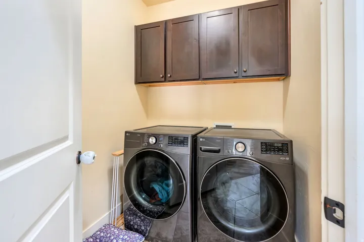 Utility area featuring overhead dark wood-finish cabinetry and light-colored walls