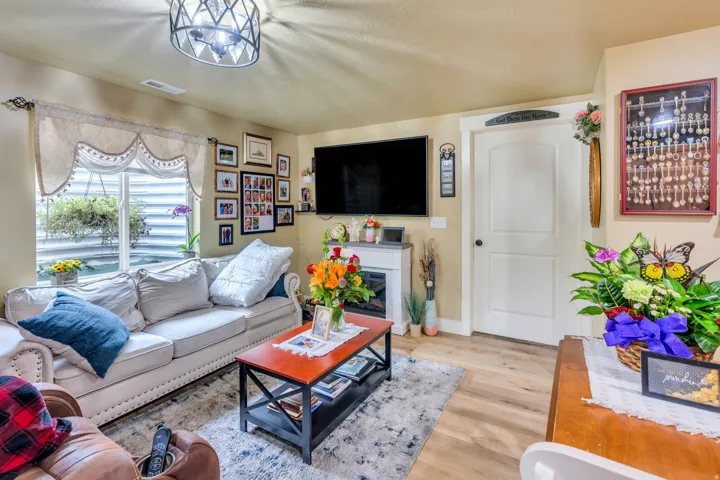 Living area featuring wood-finish flooring, a decorative fireplace, and a light fixture with geometric detailing