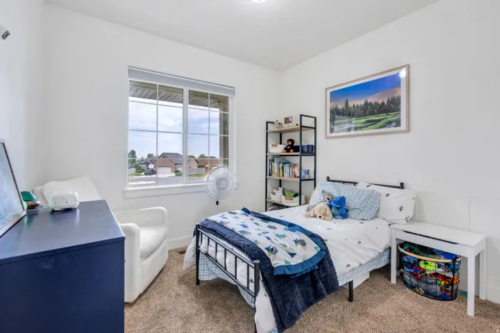 Bright room with white painted walls, natural light from a large window, brown carpet flooring, and a recessed ceiling light fixture