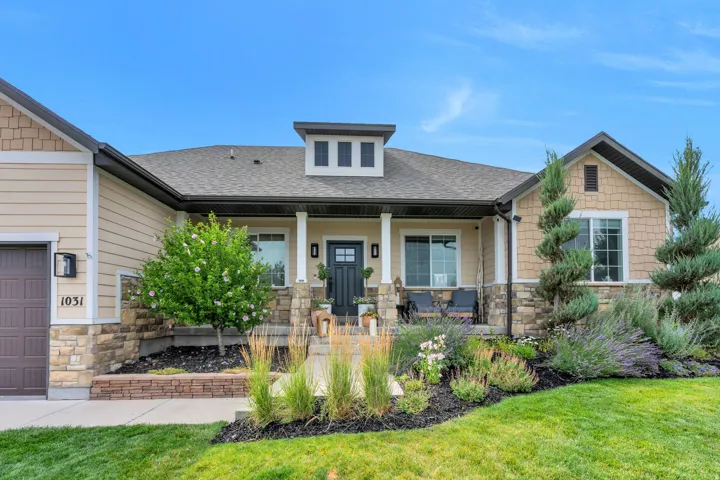 Exterior featuring a covered porch, stone accents, horizontal siding, and a prominent dormer with three windows
