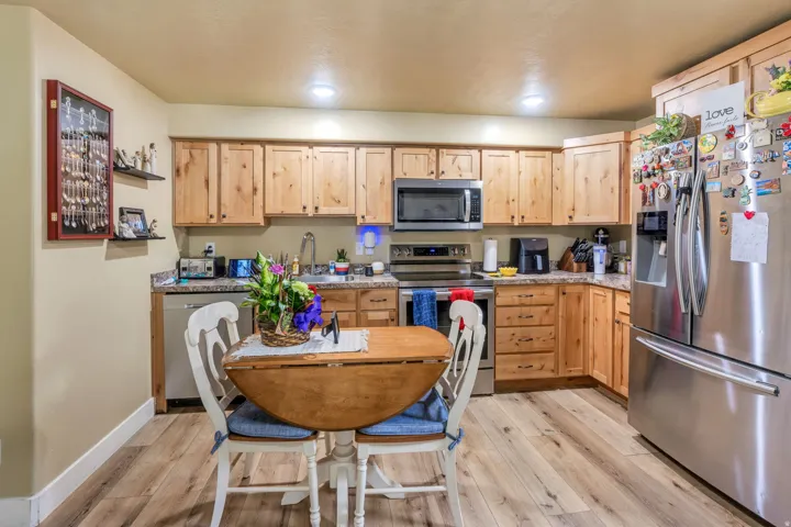 Kitchen featuring wood-finish flooring, wood cabinetry with dark hardware, stainless steel appliances, and light-toned countertops