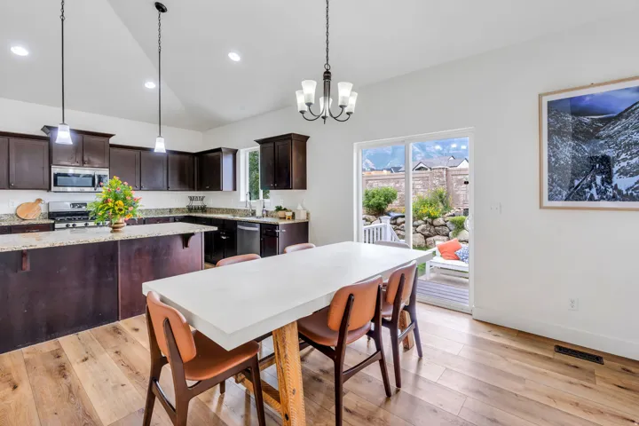 Kitchen and dining area featuring wood-finish flooring, dark wood cabinetry, and light-toned countertops