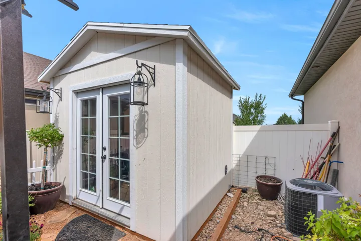 Detached outbuilding featuring white siding and double glass-paneled doors with black hardware