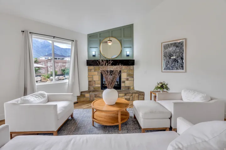 Living area featuring a stone fireplace with a dark wood mantel, a green paneled accent wall, and high ceilings
