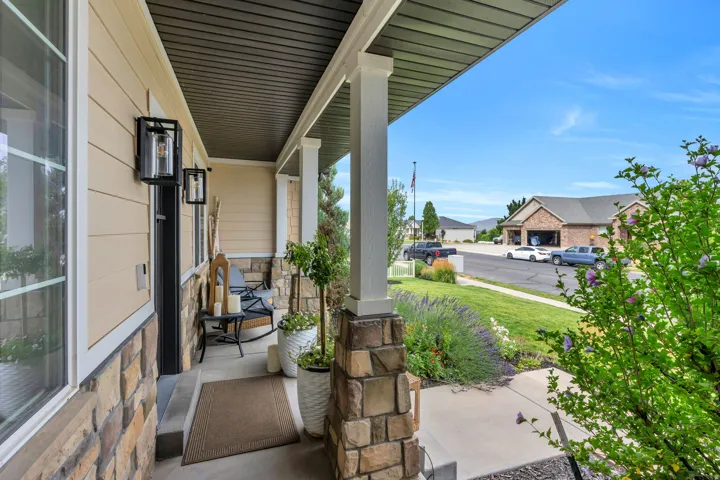 Inviting covered front porch with stone-clad columns, horizontal siding, and modern wall sconces