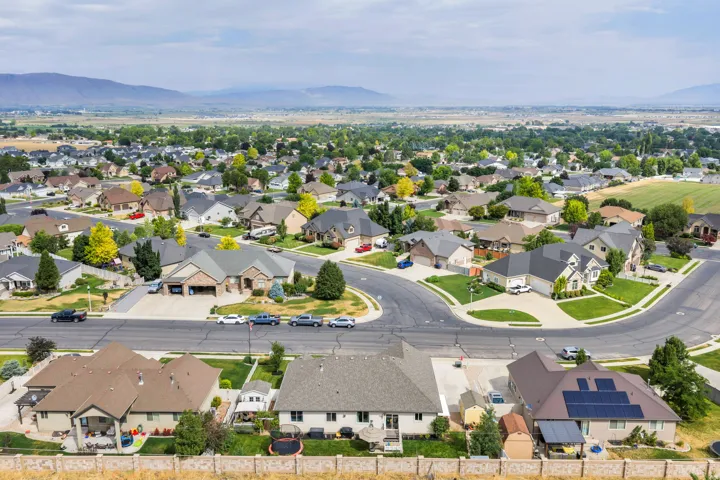 Residential neighborhood featuring established homes, mature trees, paved streets, and mountainous terrain in the distance