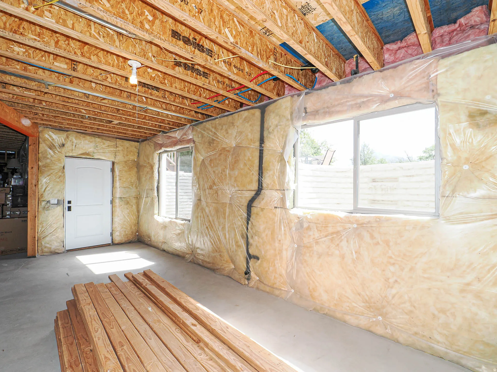 Unfinished lower level featuring exposed ceiling joists, concrete flooring, and insulated walls