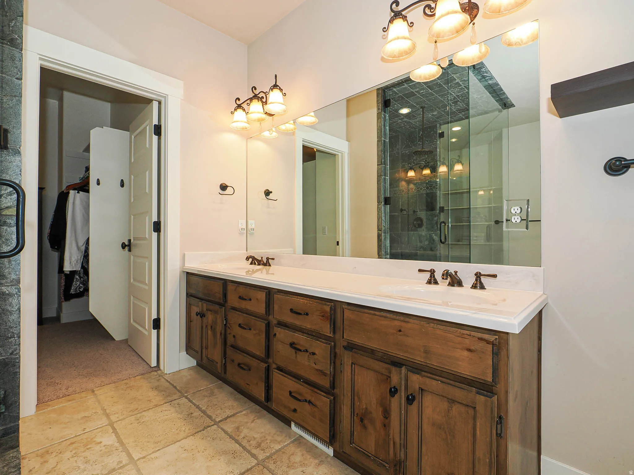Dual vanity featuring wood-finish cabinetry, white countertops, and bronze-finish fixtures