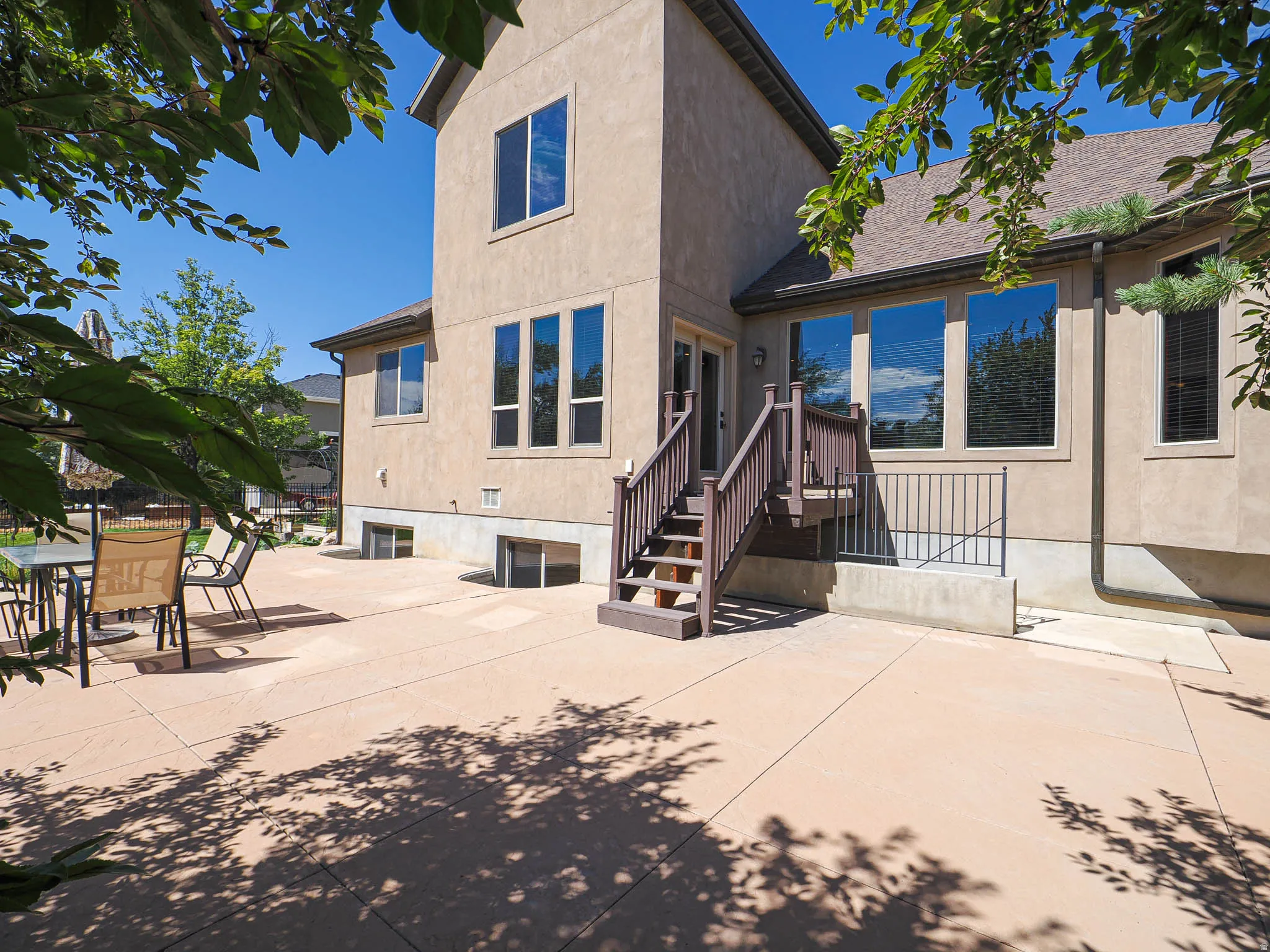 Expansive concrete patio with a tiered wood deck and stairs leading to the upper level