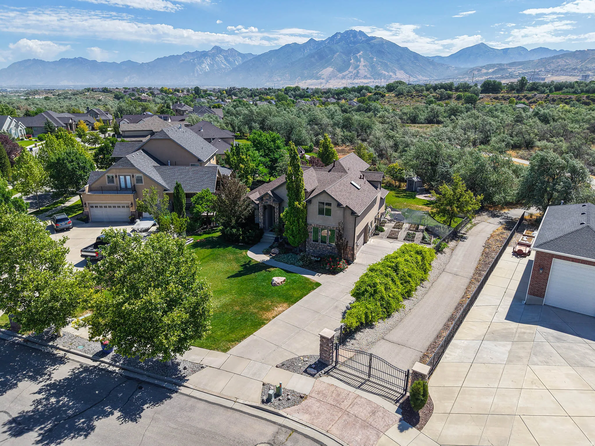 Gated entrance to a residence featuring mature landscaping and a mountain backdrop