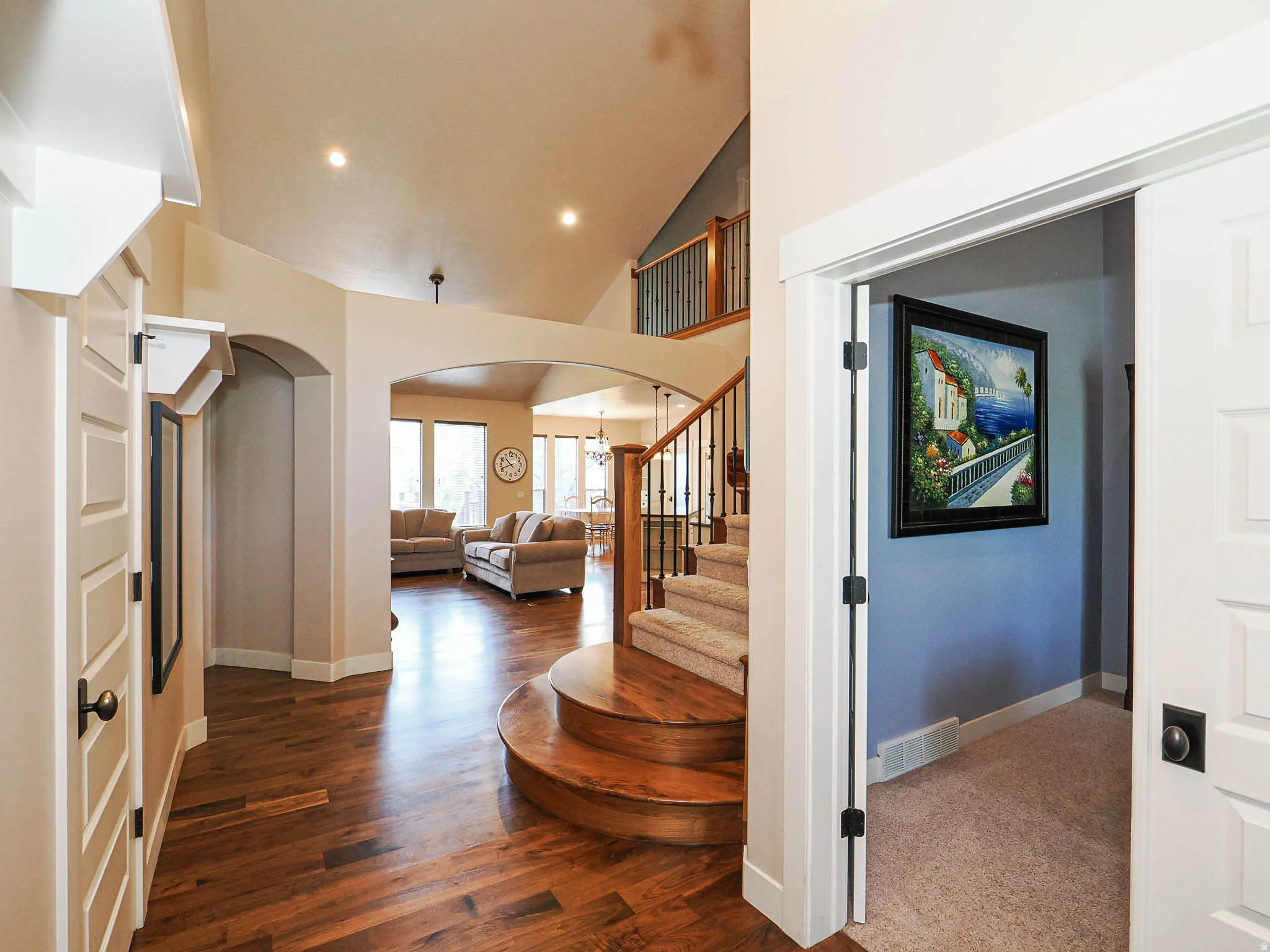 Grand foyer featuring rich wood-finish flooring, a curved staircase with carpeting, and an elegant wood and wrought iron railing