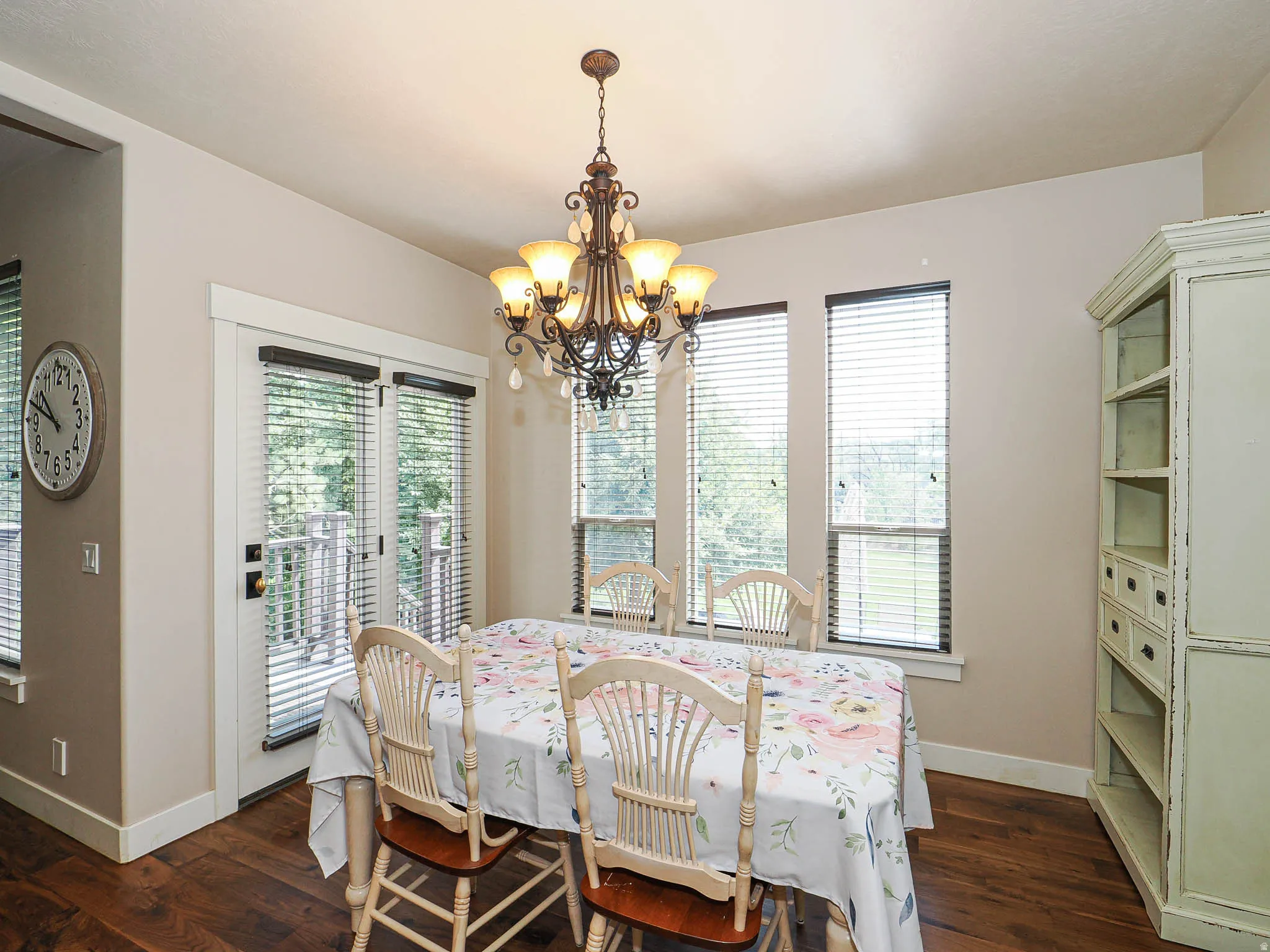 Dining area featuring wood-finish flooring, a decorative chandelier, multiple windows with blinds, and white trim