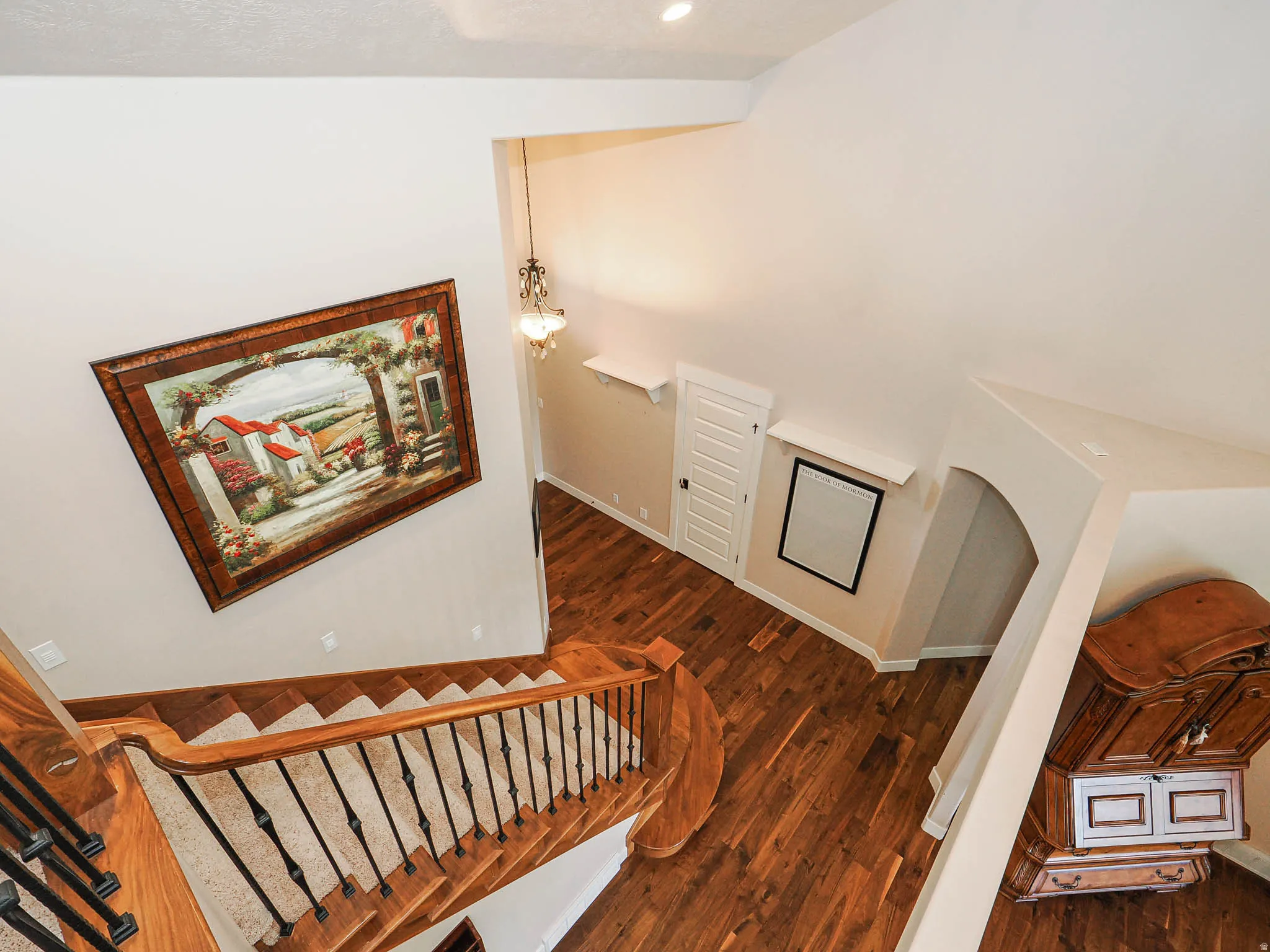 Grand staircase with wood-finish treads and risers, black wrought iron spindles, and a wood-finish handrail