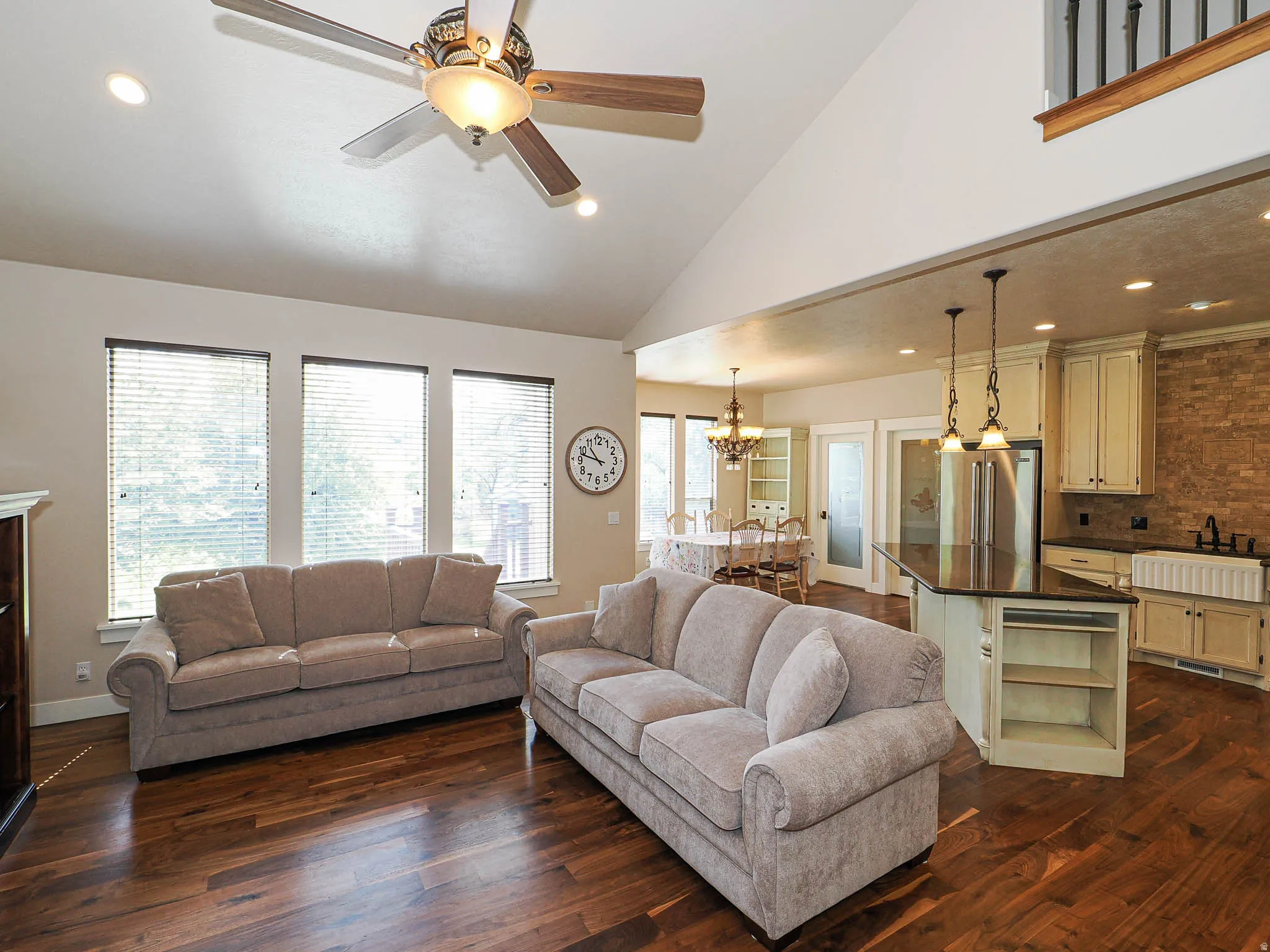 Spacious open-concept living area featuring high vaulted ceilings, recessed lighting, and wood-finish flooring