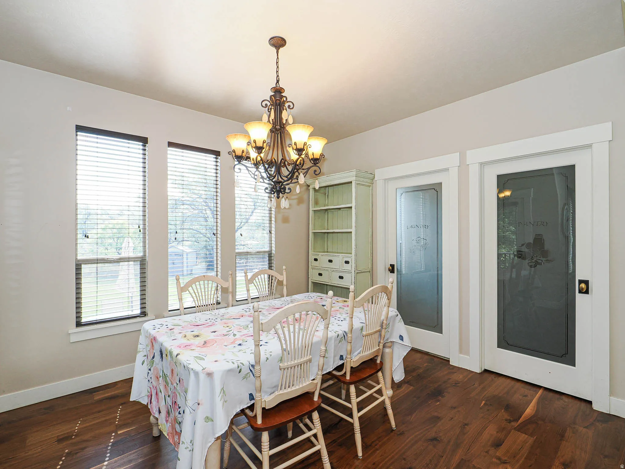 Dining area featuring wood-finish flooring, a decorative chandelier, and three large windows
