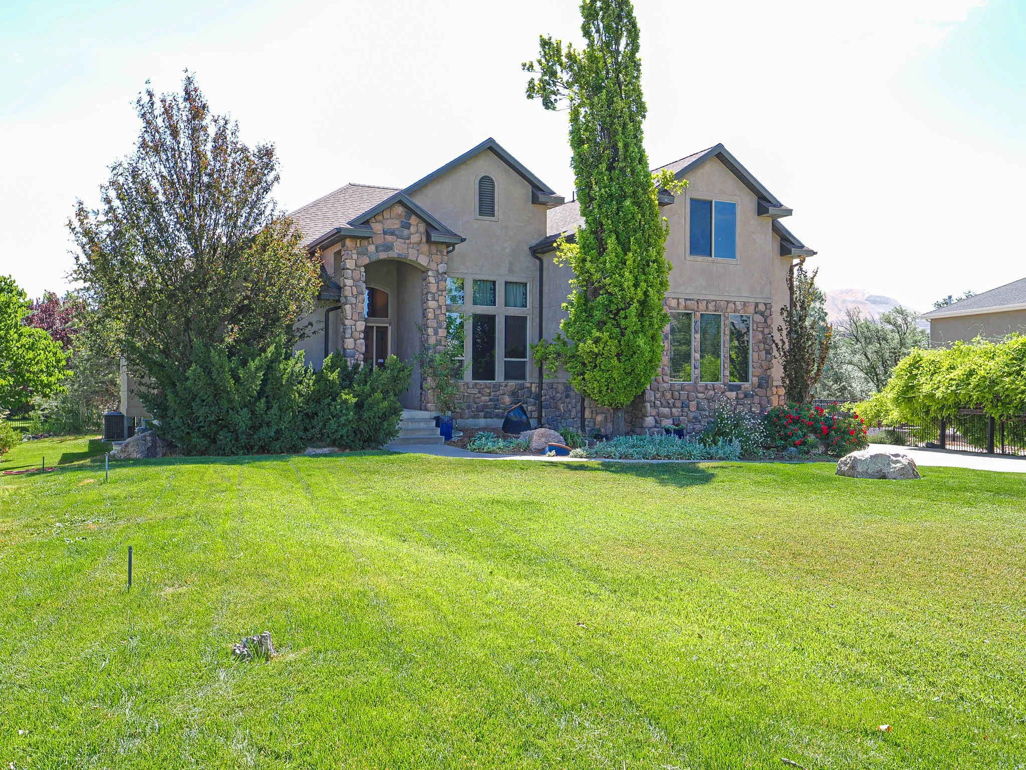 Stucco and stone exterior featuring a covered entry, multiple gables, and an attached three-car garage