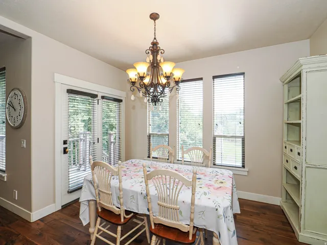 Dining area featuring wood-finish flooring, a decorative chandelier, multiple windows with blinds, and white trim