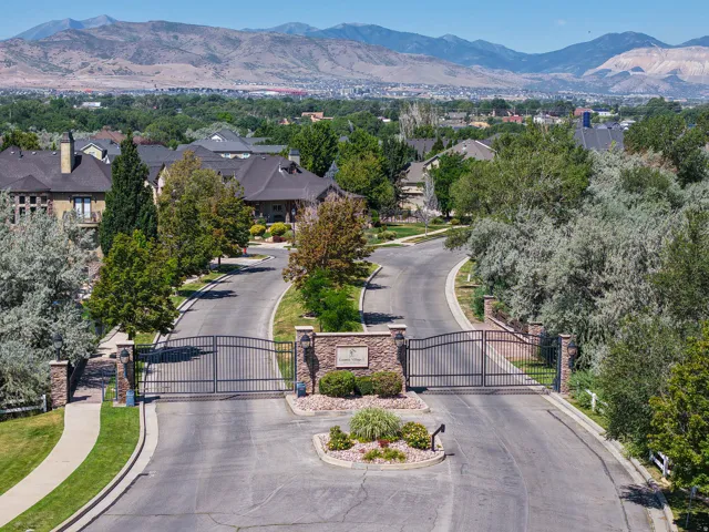 Gated community entry with stone pillars, wrought iron gates, and mature landscaping