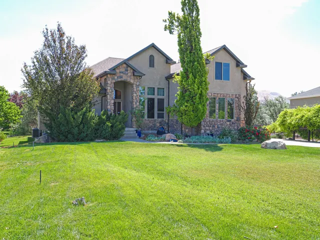 Stucco and stone exterior featuring a covered entry, multiple gables, and an attached three-car garage