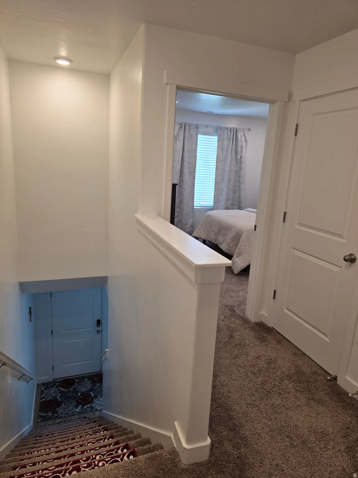 Stairwell featuring recessed lighting, a painted railing, and carpeted steps