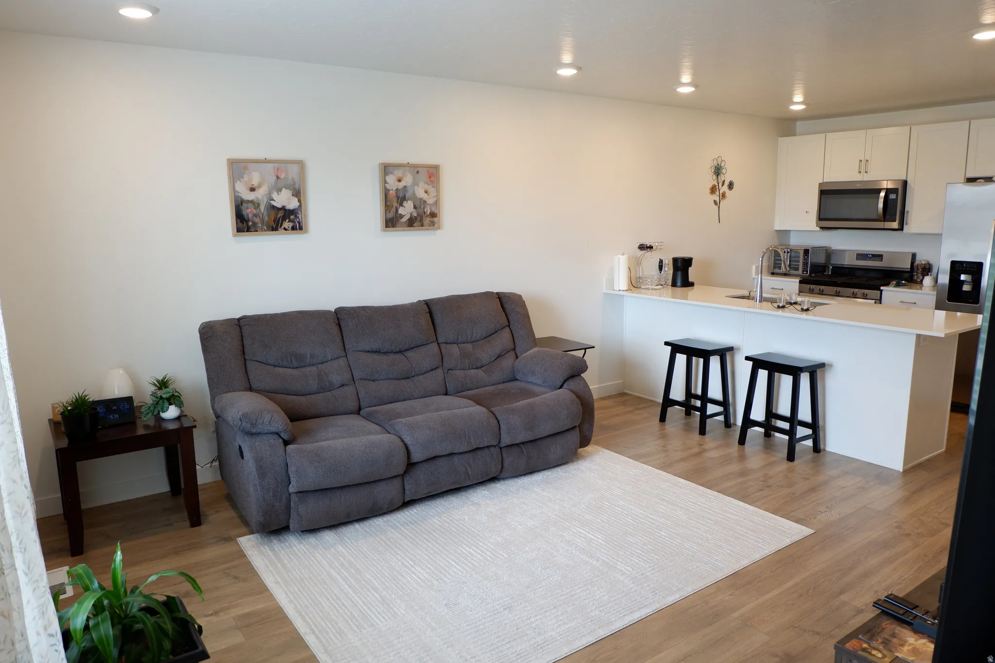 Open-concept living space with wood-finish flooring, recessed lighting, and a neutral color palette