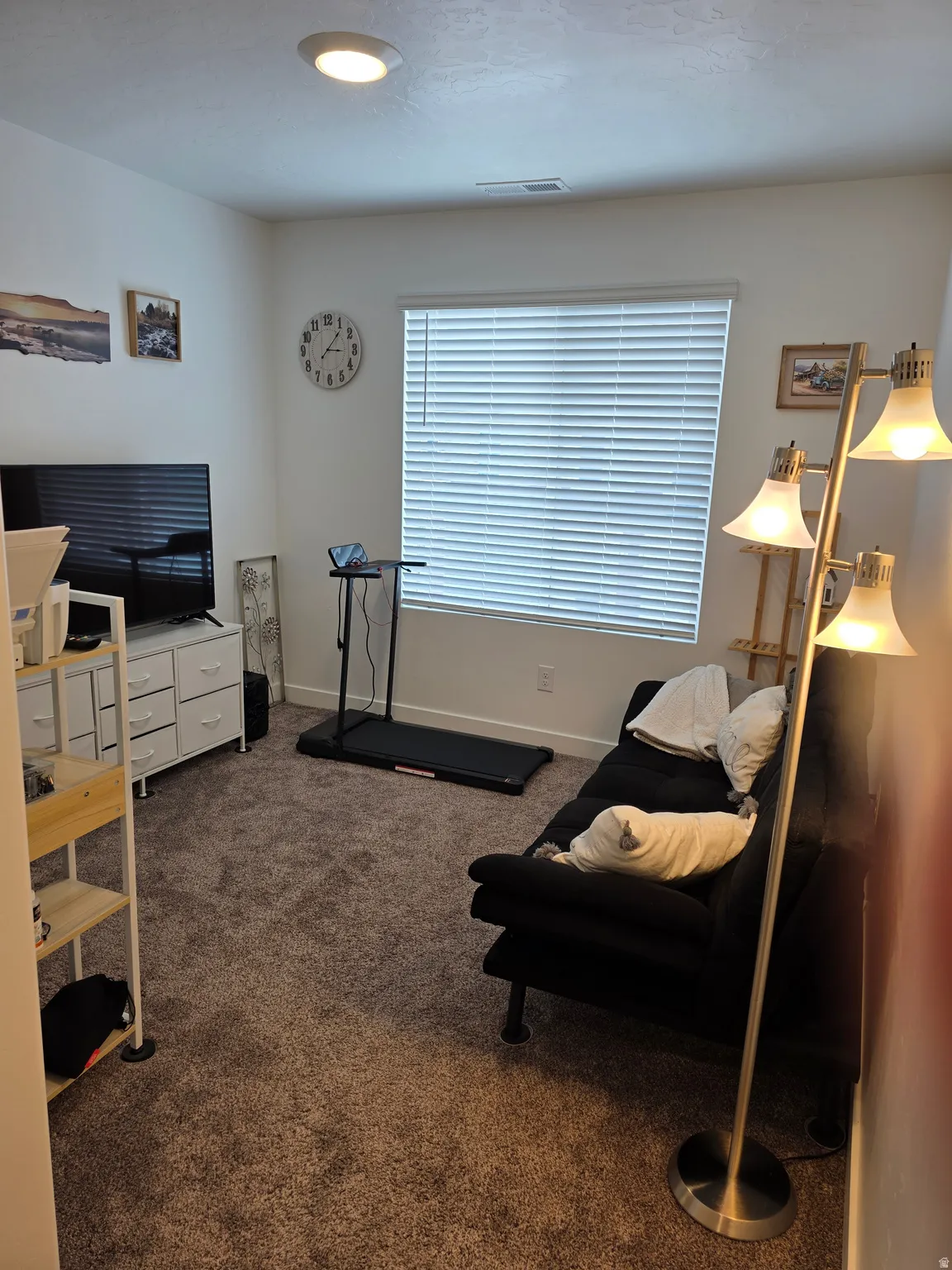 Carpeted room featuring a window with blinds, white walls, and a ceiling-mounted light fixture