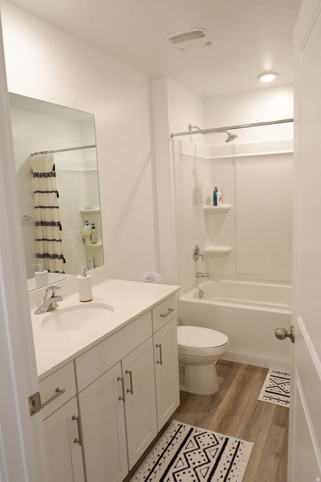 Bathroom featuring a white vanity with slab countertop, undermount sink, and brushed nickel faucet