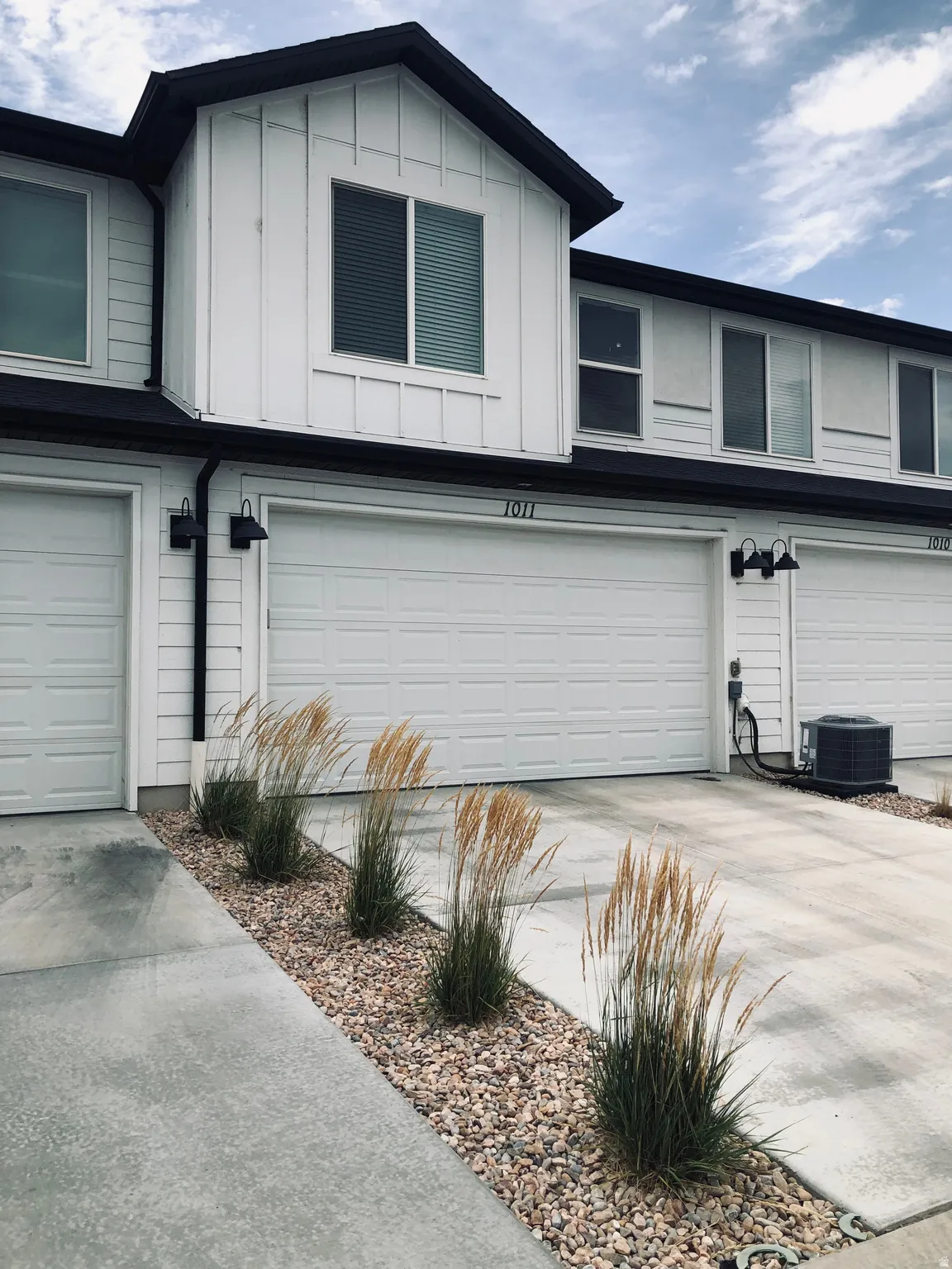 Modern townhome exterior with crisp white vertical siding and dark trim accents