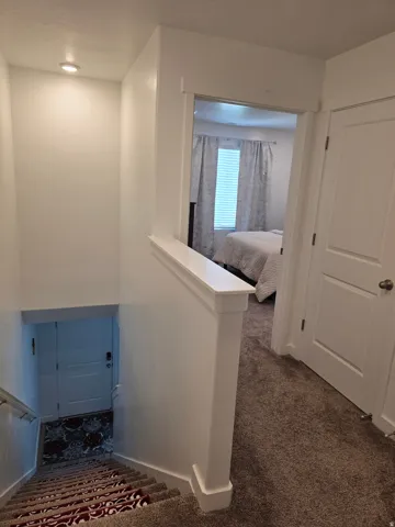 Stairwell featuring recessed lighting, a painted railing, and carpeted steps
