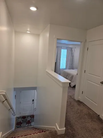Carpeted staircase with white handrail and recessed lighting
