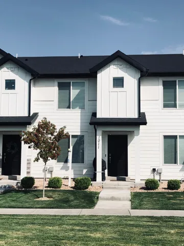 Contemporary townhouse exterior featuring white siding, black trim, and a matching black roof