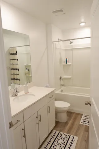 Bathroom featuring a white vanity with slab countertop, undermount sink, and brushed nickel faucet
