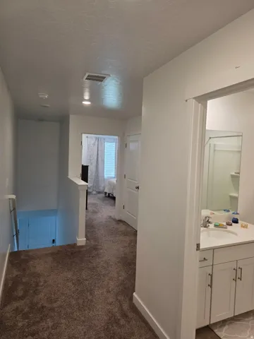 Carpeted hallway featuring a white banister and recessed lighting