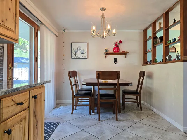 Dining area featuring tiled flooring, a contemporary chandelier, and built-in shelving