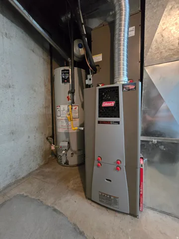 Utility area featuring a water heater, furnace, and exposed ductwork