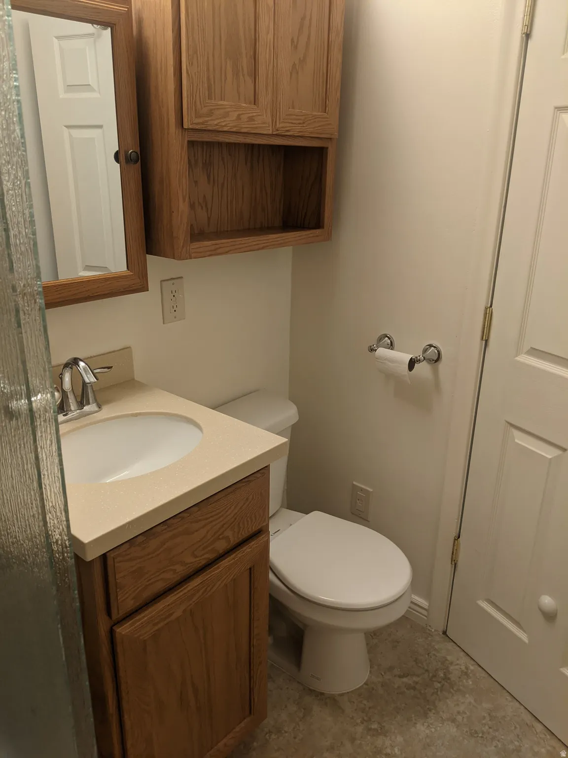 Bathroom featuring a single vanity with a countertop, an integrated sink, and wood-finish cabinetry