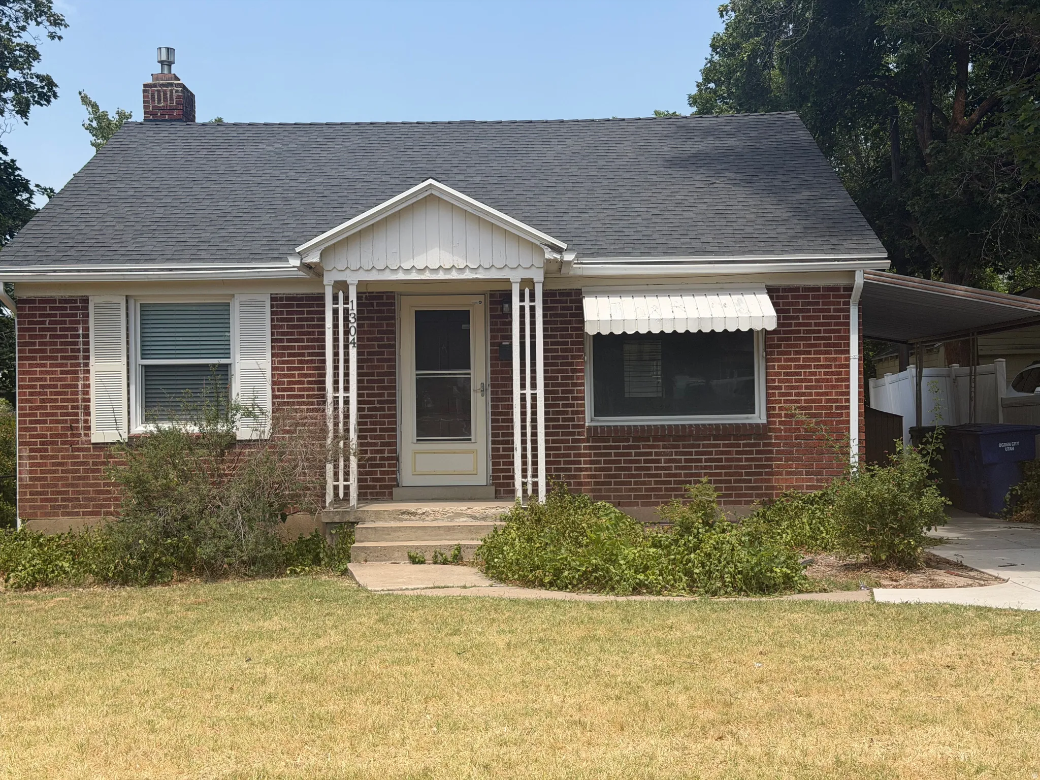 Brick facade home with a covered front porch and a dark shingle roof